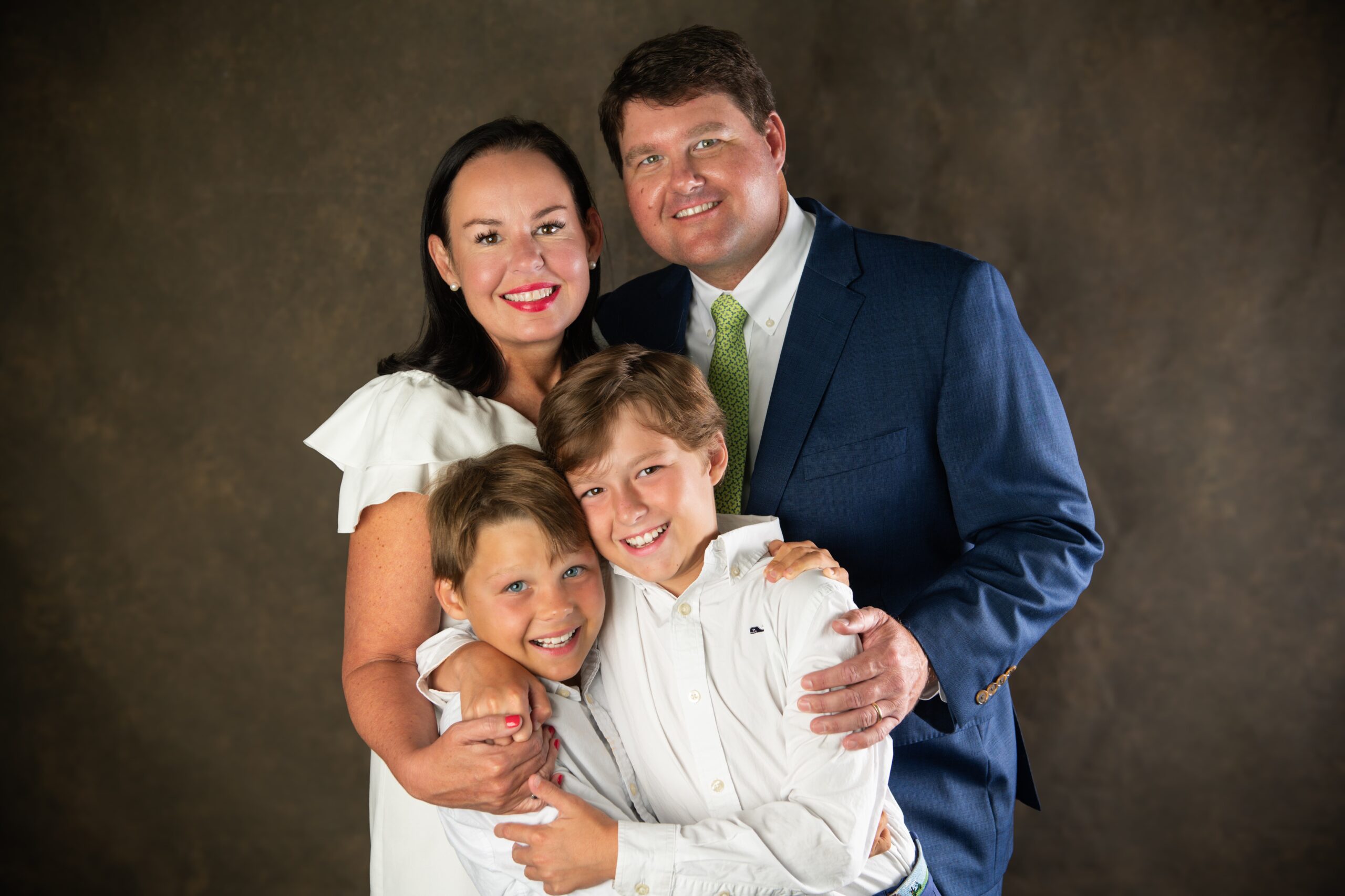 Family of four in navy and white against a dark studio backdrop