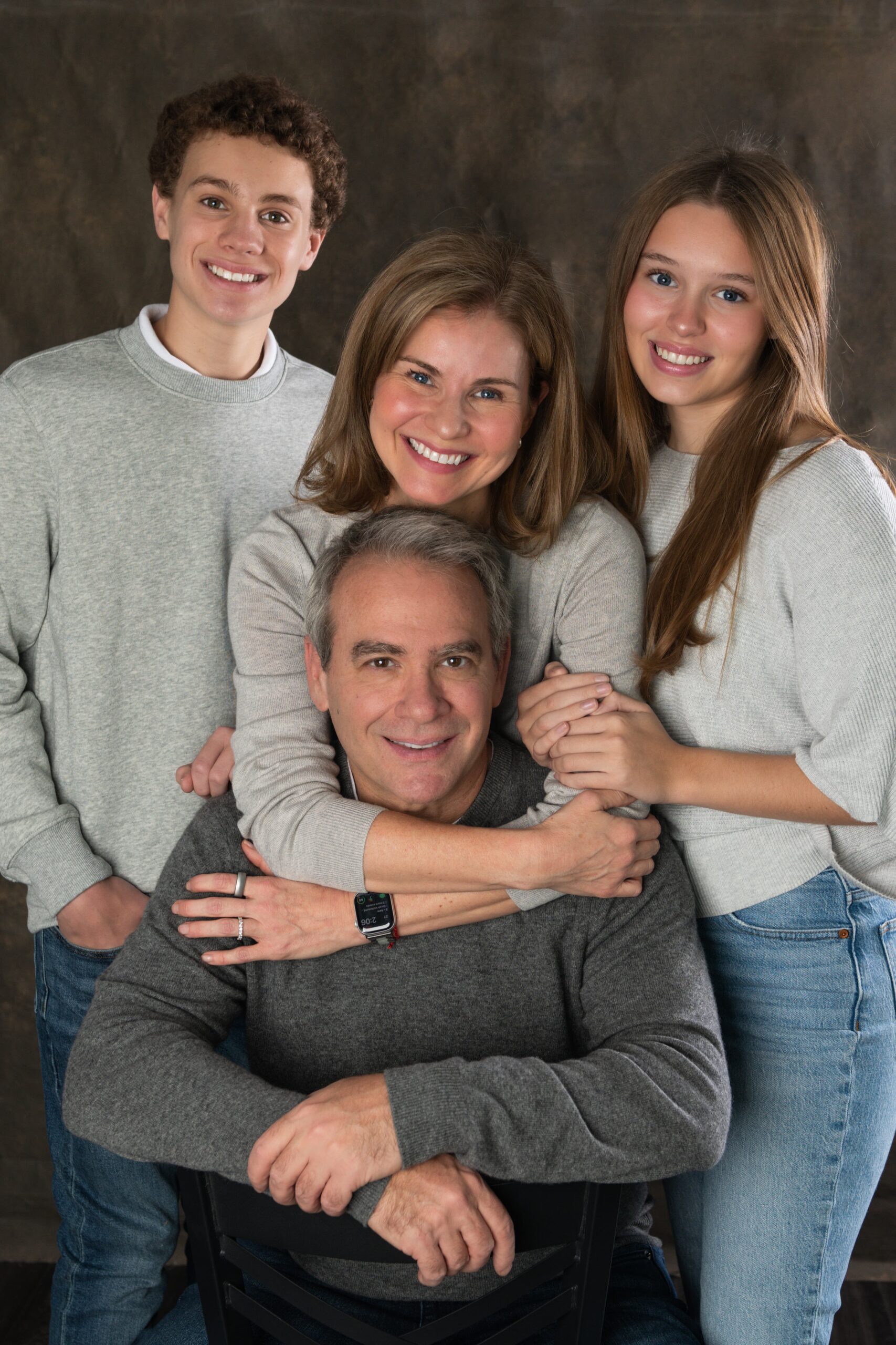Parents with their teenage son and daughter in coordinated gray tops
